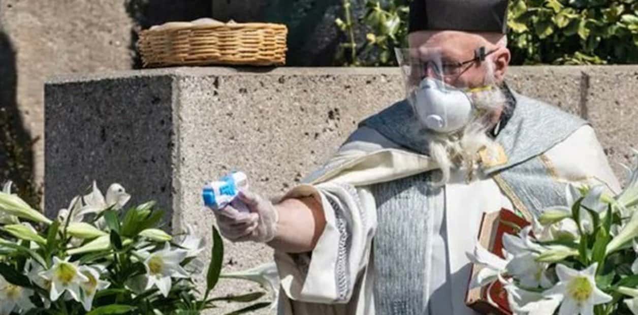 Un sacerdote utiliza una pistola de agua para realizar las bendiciones