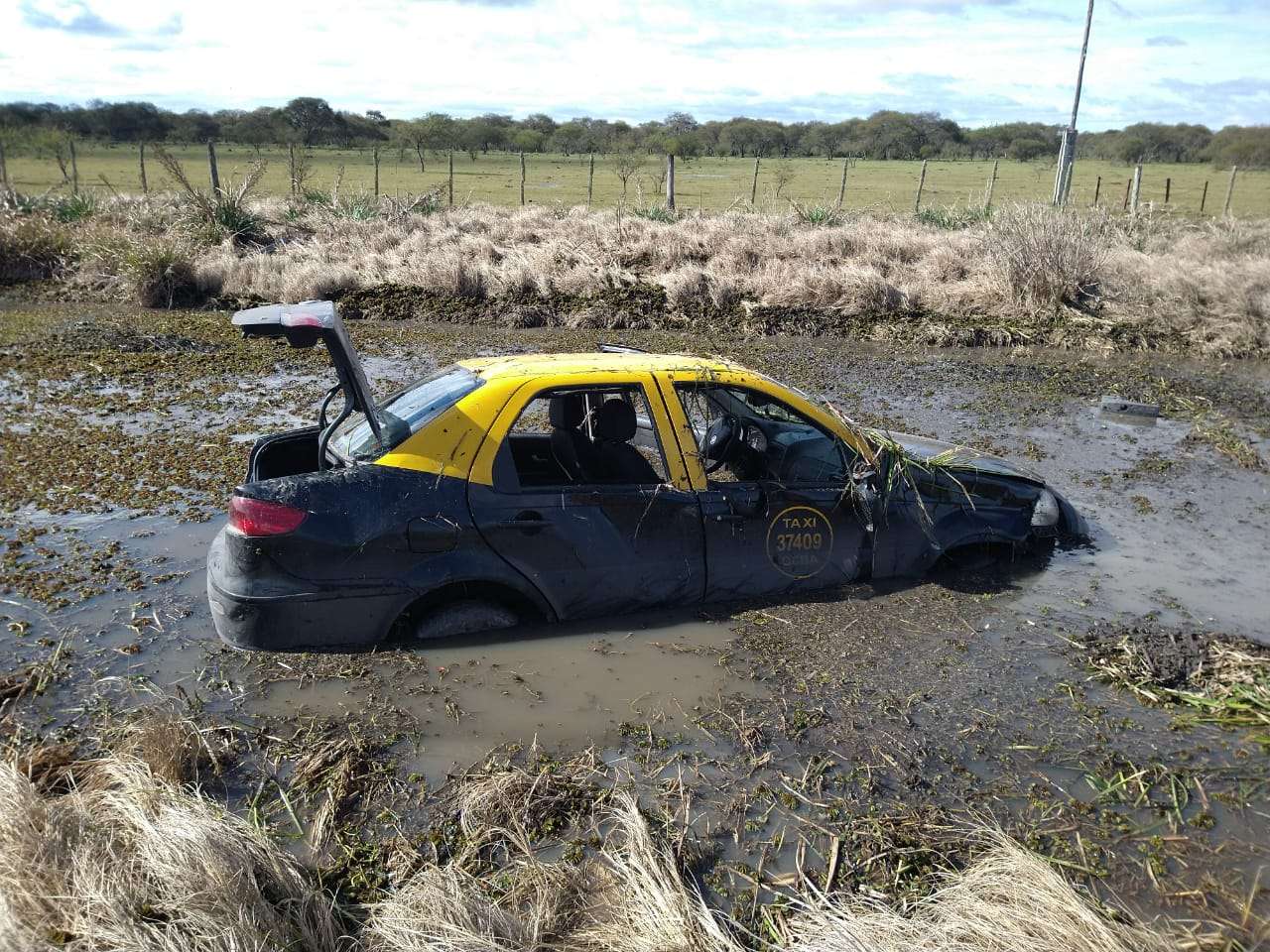 Tras un despiste, un taxi volcó y terminó encajado en una laguna de barro